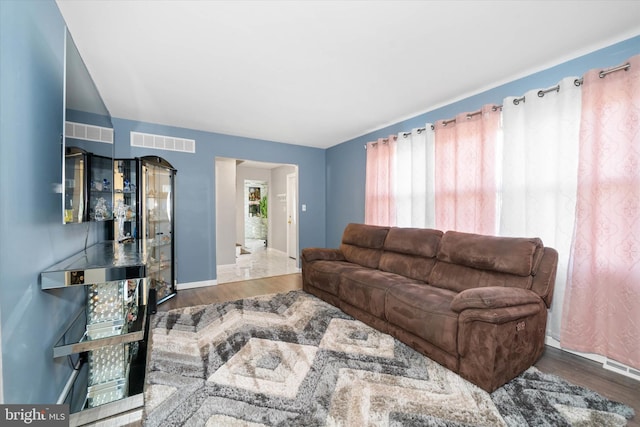 living area featuring a wealth of natural light, visible vents, baseboards, and wood finished floors