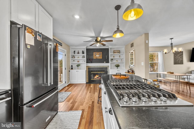 kitchen featuring stainless steel appliances, a fireplace with flush hearth, white cabinetry, and light wood finished floors