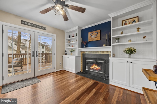 living area with french doors, a fireplace with flush hearth, dark wood finished floors, and built in features