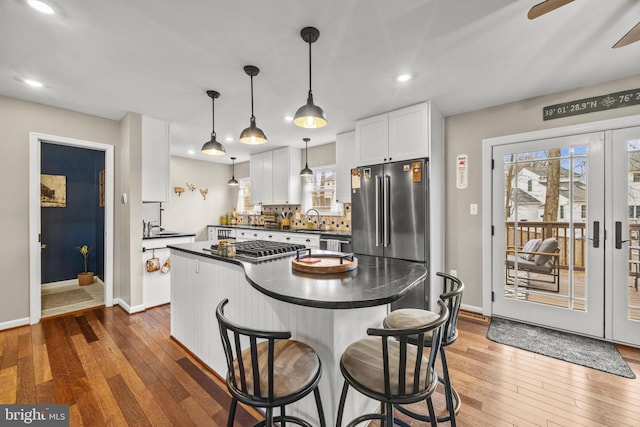 kitchen featuring dark countertops, wood-type flooring, white cabinets, and a sink