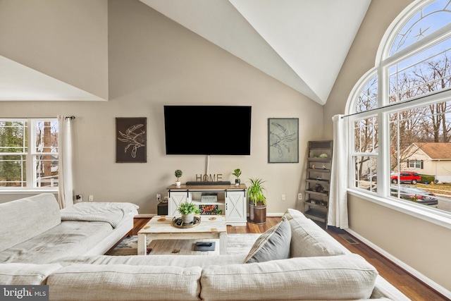 living area with high vaulted ceiling, baseboards, and wood finished floors