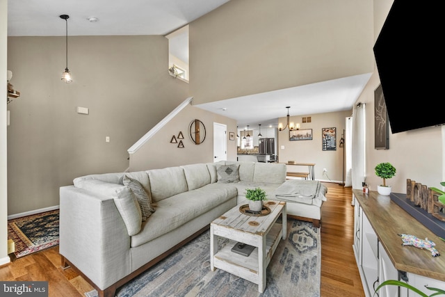 living area featuring a chandelier, high vaulted ceiling, light wood-type flooring, and visible vents