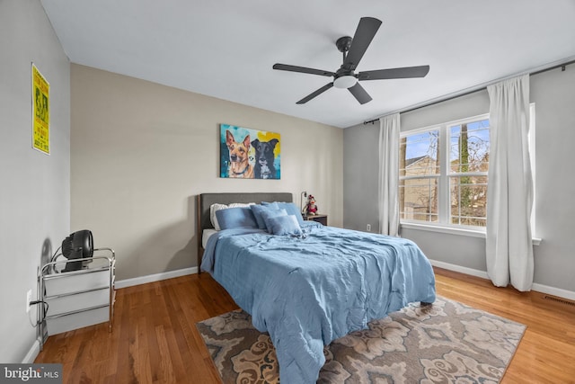 bedroom featuring visible vents, ceiling fan, baseboards, and wood finished floors