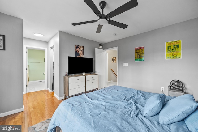 bedroom featuring light wood-type flooring, ensuite bath, a ceiling fan, and baseboards