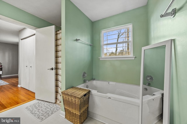 bathroom featuring baseboards and a bath