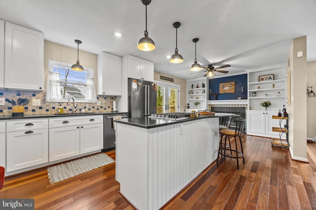 kitchen featuring stainless steel appliances, dark countertops, a sink, and white cabinets