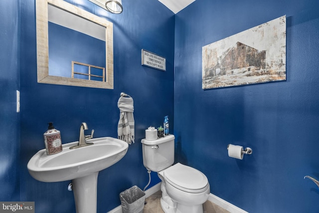 bathroom featuring tile patterned flooring, baseboards, a sink, and toilet