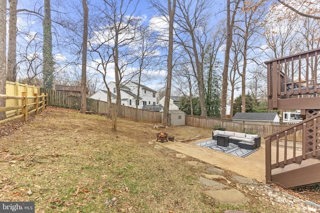 view of yard with an outdoor living space with a fire pit, an outdoor structure, a fenced backyard, and a shed