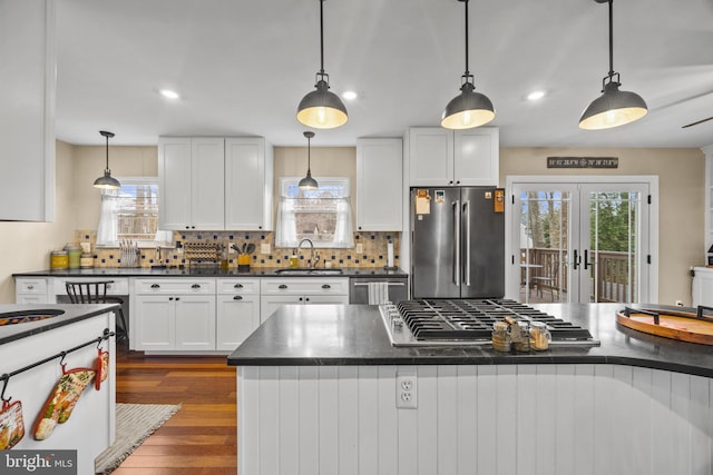 kitchen featuring dark countertops, decorative backsplash, appliances with stainless steel finishes, dark wood-type flooring, and a sink