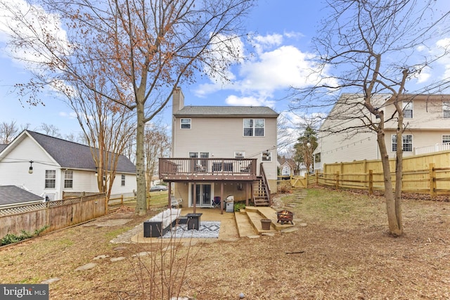 rear view of property with a fire pit, a patio, a fenced backyard, a chimney, and a deck