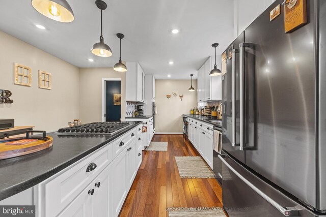 kitchen with stainless steel appliances, dark countertops, and white cabinetry