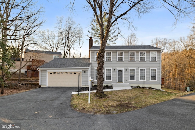 view of front of property with aphalt driveway, a shingled roof, a chimney, and an attached garage