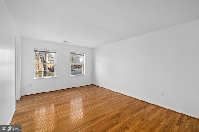 empty room with light wood-type flooring and visible vents