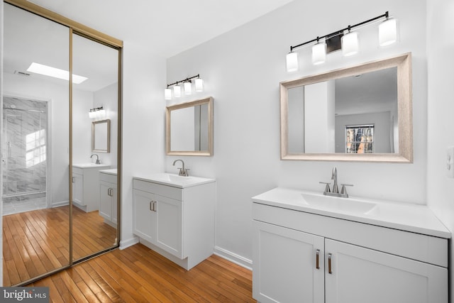 bathroom featuring hardwood / wood-style flooring, two vanities, and a sink