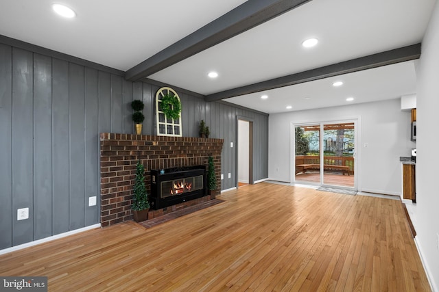 unfurnished living room featuring light wood-style flooring, recessed lighting, a fireplace, baseboards, and beamed ceiling