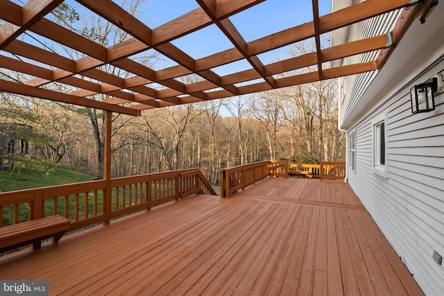 deck featuring a forest view and a pergola