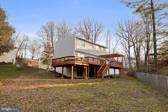 rear view of house with fence, a lawn, a wooden deck, and stairs