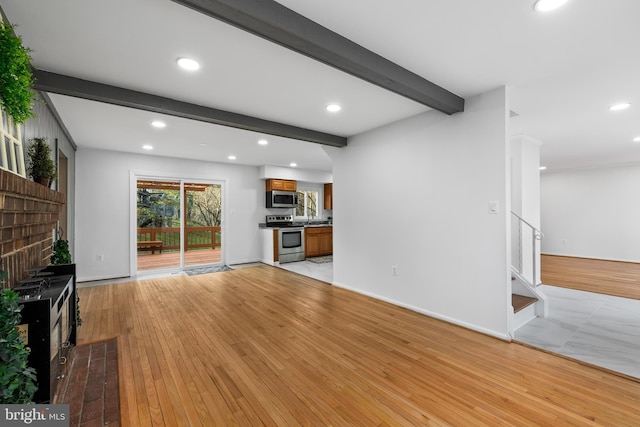 unfurnished living room with light wood-style floors, recessed lighting, beamed ceiling, and stairs