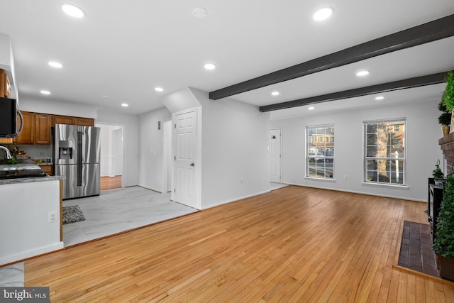 unfurnished living room featuring recessed lighting, beam ceiling, and light wood finished floors