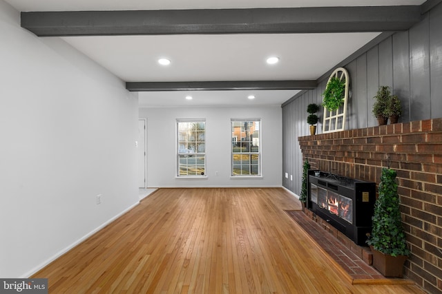 unfurnished living room featuring baseboards, light wood-style flooring, a fireplace, beam ceiling, and recessed lighting