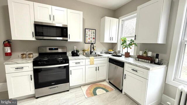 kitchen with white cabinetry, radiator heating unit, appliances with stainless steel finishes, and a sink