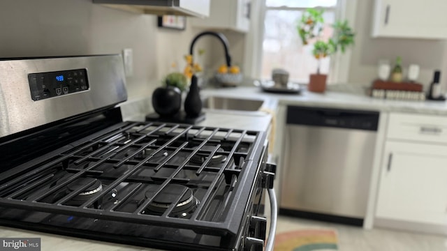 kitchen with white cabinets, a sink, stainless steel appliances, and light countertops