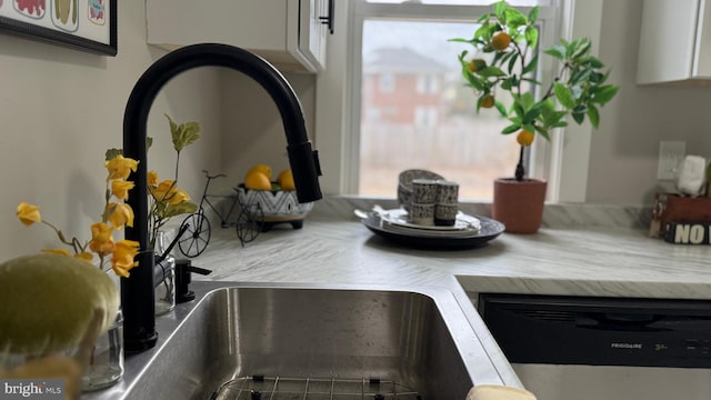 details with white cabinetry, light countertops, and dishwasher