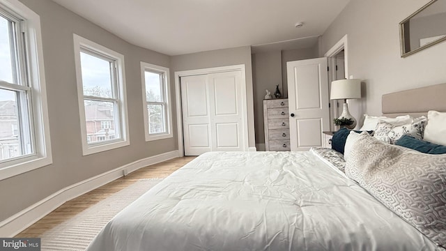 bedroom featuring a closet, wood finished floors, and baseboards