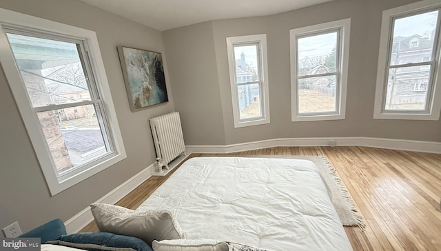 unfurnished room featuring baseboards, radiator heating unit, and wood finished floors