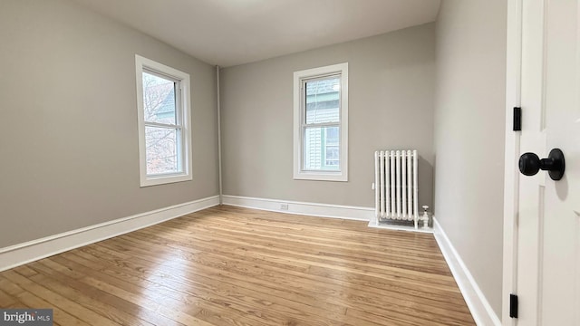 empty room with light wood-style floors, a healthy amount of sunlight, and radiator