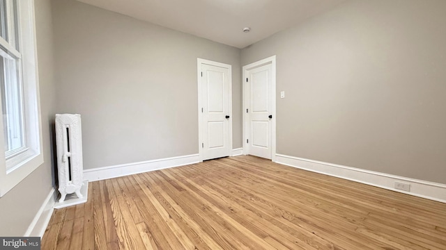 spare room featuring baseboards and light wood finished floors