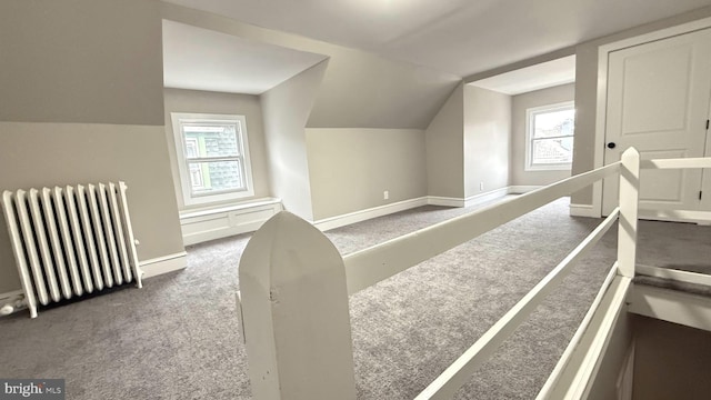 additional living space featuring carpet floors, lofted ceiling, baseboards, and radiator heating unit