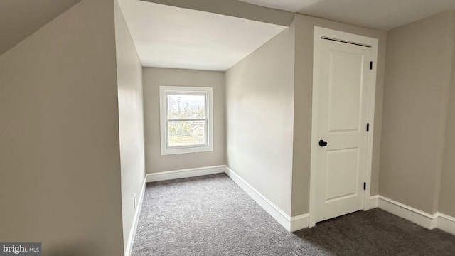 bonus room featuring baseboards and dark colored carpet