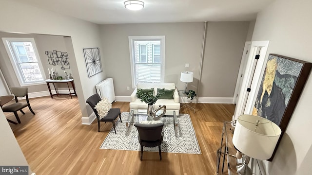 sitting room featuring radiator heating unit, baseboards, and wood finished floors