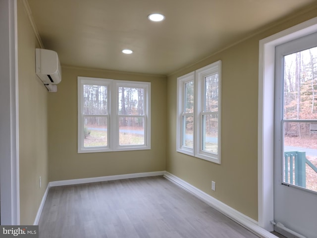 empty room with recessed lighting, a wall mounted air conditioner, wood finished floors, and baseboards