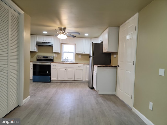 kitchen with baseboards, stainless steel electric range, under cabinet range hood, white cabinetry, and a sink