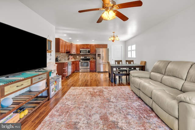 living area with ceiling fan with notable chandelier, recessed lighting, and light wood-style floors