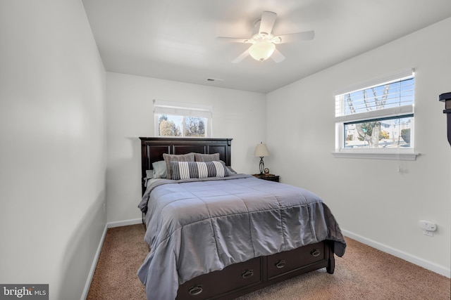 carpeted bedroom featuring visible vents, multiple windows, a ceiling fan, and baseboards