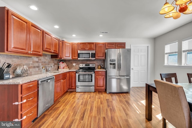 kitchen with visible vents, decorative backsplash, light wood-style flooring, stainless steel appliances, and a sink