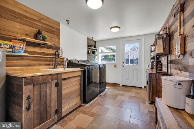 laundry room featuring laundry area, stone finish floor, separate washer and dryer, and a sink