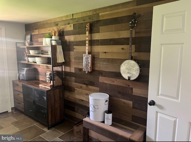 bathroom featuring decorative backsplash, wooden walls, and stone finish floor