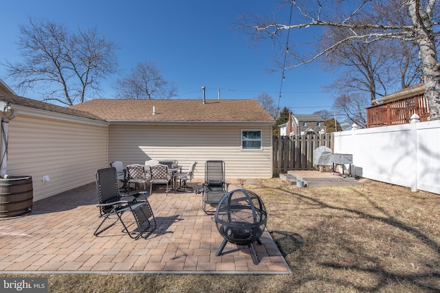 rear view of house with outdoor dining space, a patio, an outdoor fire pit, fence, and a yard