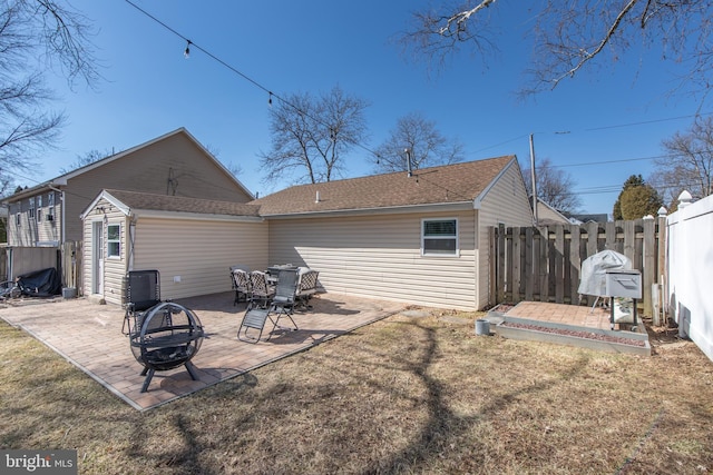 back of property with a yard, a patio area, fence, and a fire pit