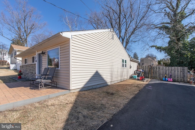 view of property exterior with a patio and fence