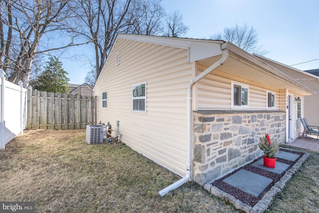 view of side of property with a yard, central AC unit, and a fenced backyard