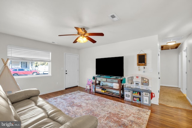 living area with visible vents, attic access, ceiling fan, and wood finished floors