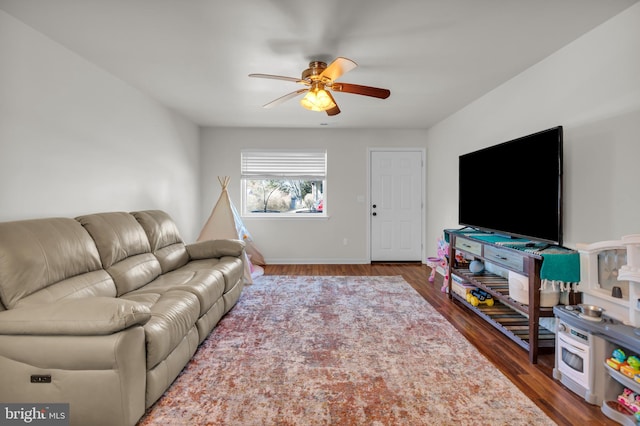 living room featuring ceiling fan, baseboards, and wood finished floors