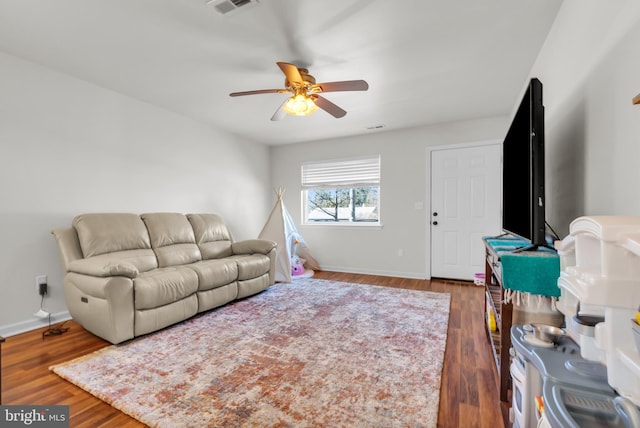 living room with a ceiling fan, baseboards, and wood finished floors