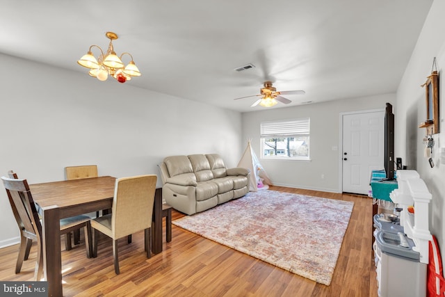 living room with visible vents, baseboards, light wood-style floors, and ceiling fan with notable chandelier