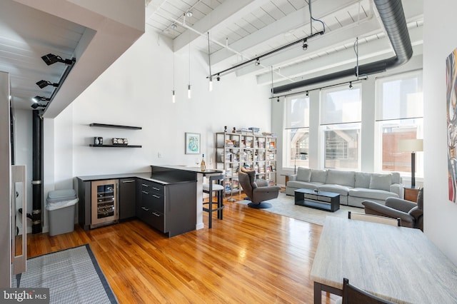 interior space with wine cooler, a dry bar, rail lighting, and light wood finished floors